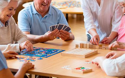 Пожилые люди весело проводят время за настольными играми